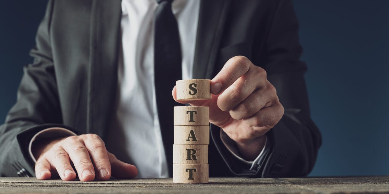 Businessman stacking wooden cut circles to assemble the word Start in a conceptual image.