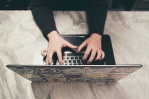A professional working at a laptop on a marble desk, representing the process of creating valuable blog content for a business website.