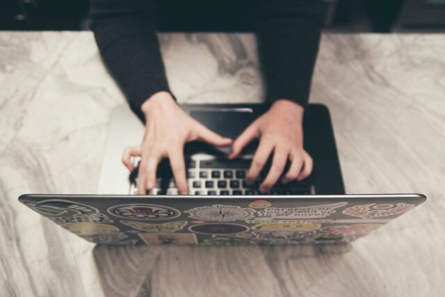 A professional working at a laptop on a marble desk, representing the process of creating valuable blog content for a business website.
